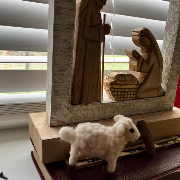 A small needle-felted lamb displayed on books